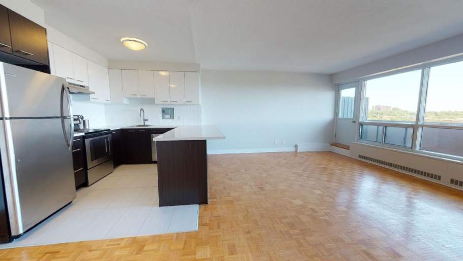 Open concept living room with parquet flooring and kitchen with stainless steel appliances