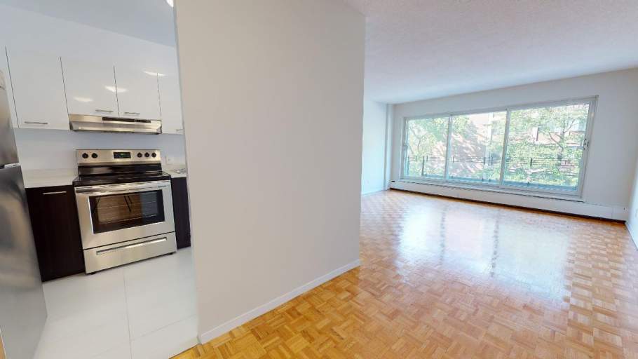 Open concept living room with parquet flooring, kitchen, and sliding door to the balcony